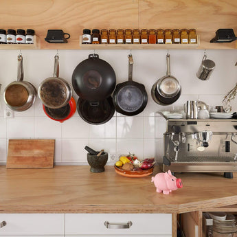 Modern kitchen setup with hanging pots, spices, espresso machine, and countertop essentials.